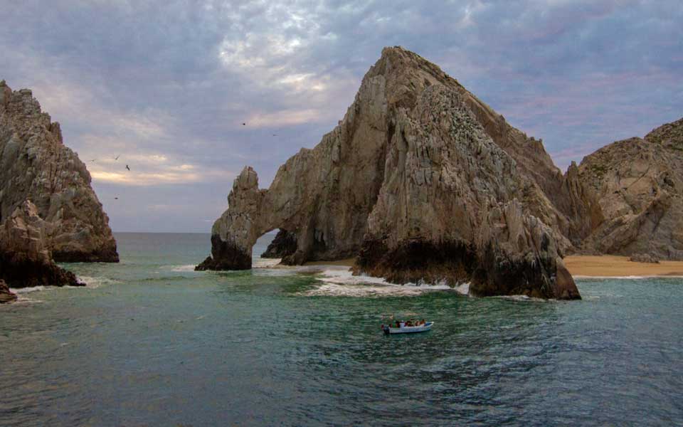 Sunset sky and Land's End bathed in color on a Cabo Rey dinner cruise